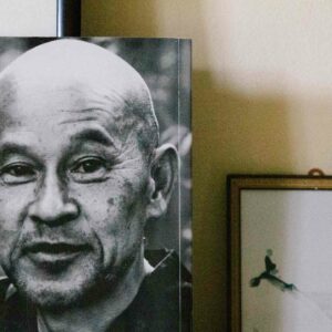 Buchcover Zen Geist Anfänger Geist mit dem Kopf von Shunryu Suzuki Roshi neben einem Bild an die Wand gelehnt